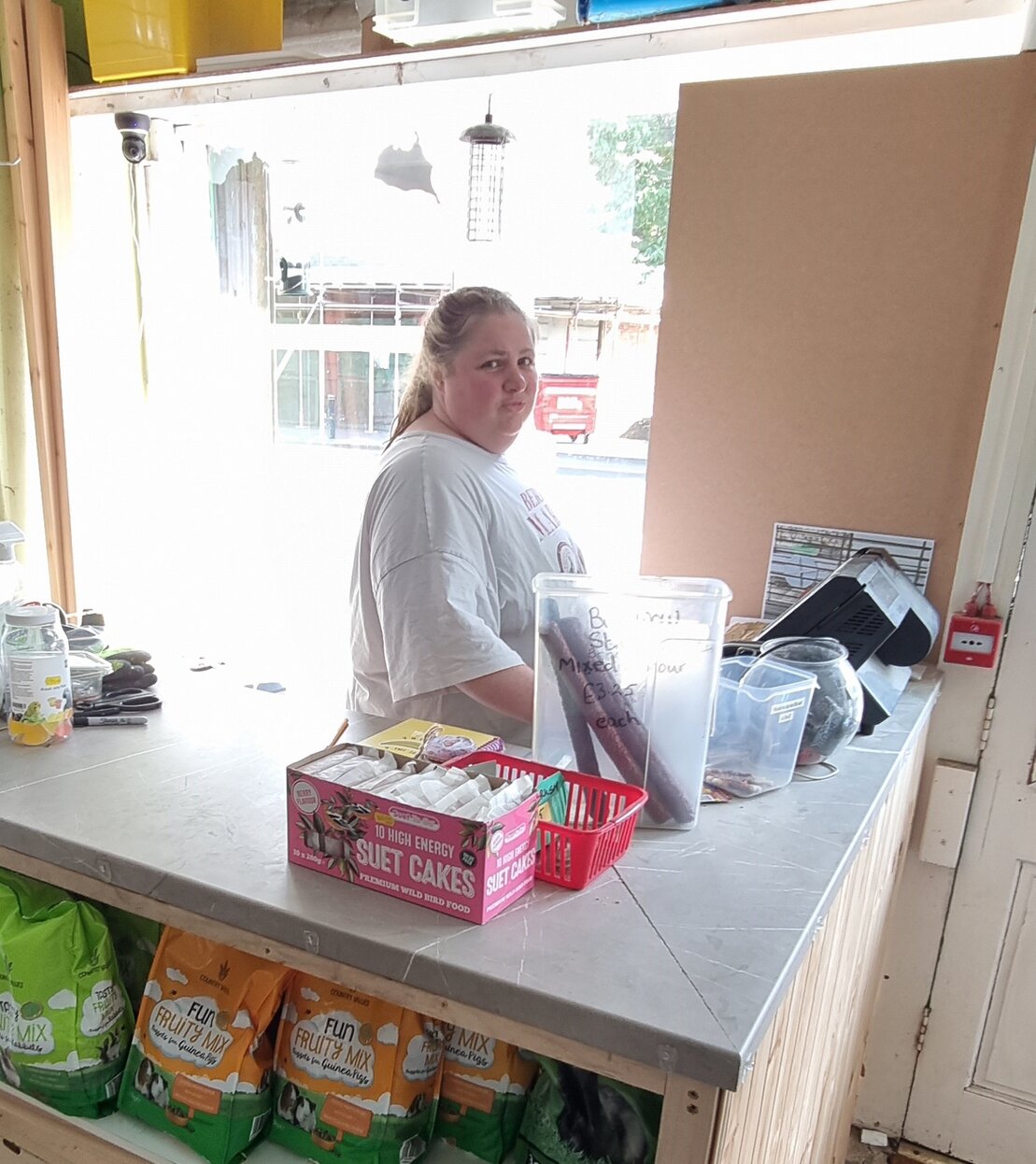 Heather, the shop owner, smiling in front of pet supplies